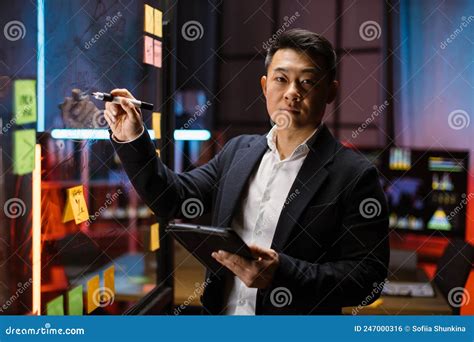 Focused Smart Asian Businessman Drawing Graphs On Glass Presentation