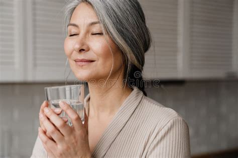 Mature Grey Woman Smiling While Drinking Water In Kitchen Stock Photo Image Of Kitchen Smile