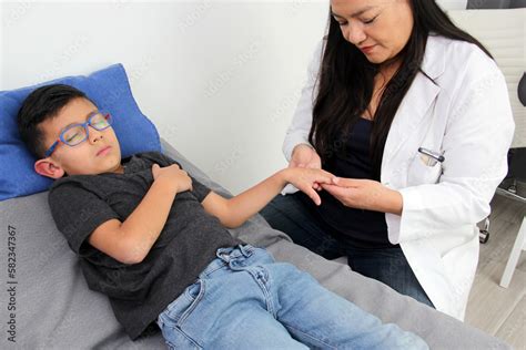 Latina Female Pediatrician Doctor Attends To Her Year Old Boy Patient Checks Her Fingers