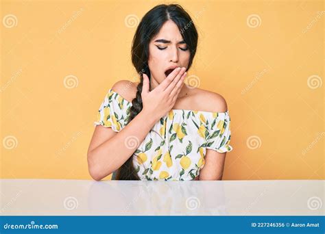 Una Adolescente De Brunette Con Ropa Casual Sentada En La Mesa Aburrida