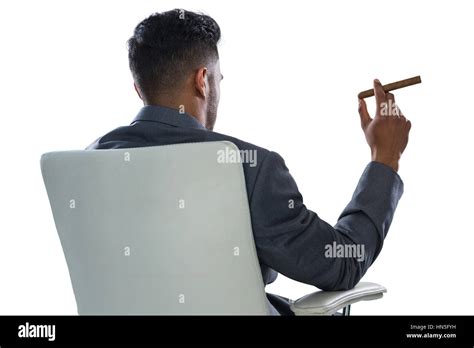 Rear View Of Businessman Holding Cigar Against White Background Stock