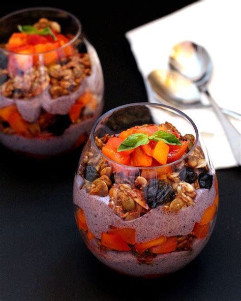 Two Glasses Filled With Fruit And Nuts On Top Of A Black Table Next To