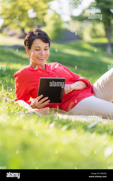 Mature Woman Lying On Grass And Using Digital Tablet Stock Photo Alamy