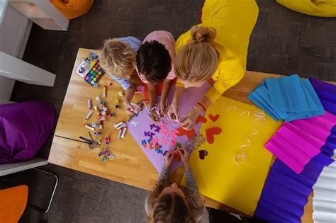 Premium Photo Making Cutouts Top View Of Blonde Teacher And Pupils Using Color Paper For