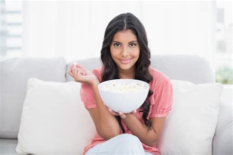 Content Cute Brunette Sitting On Couch Holding Popcorn Bowl Premium Photo