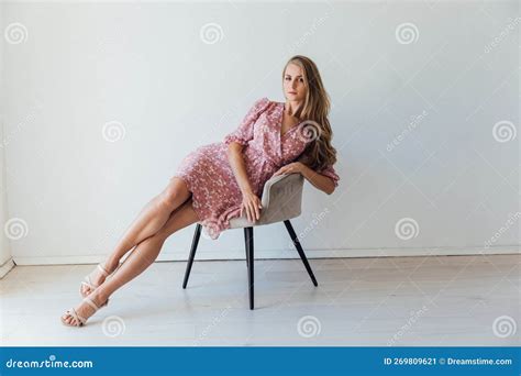 Beautiful Blonde Woman In A Colored Pink Dress Sits On A Chair Stock Image Image Of Makeup