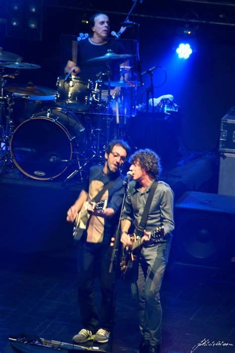 Two Men Standing On Stage With Guitars And Drums In Front Of Them One