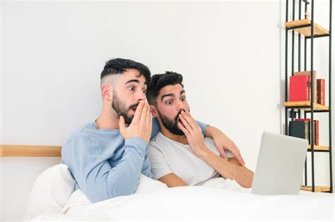 Casal Gay Jovem Chocado Sentado Na Cama Olhando Para Laptop Foto Gr Tis