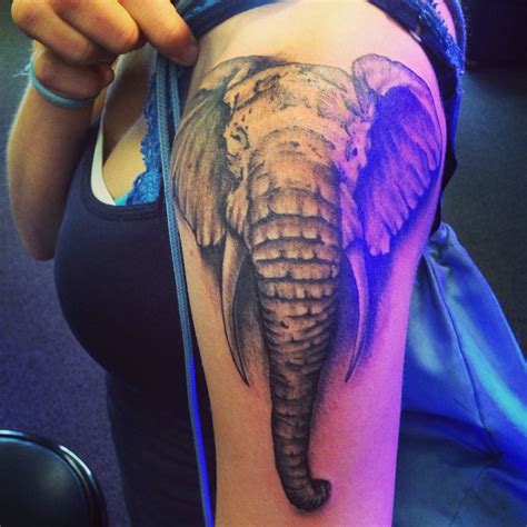 An Elephant Tattoo On The Right Arm And Shoulder With Purple Light Coming From Behind It