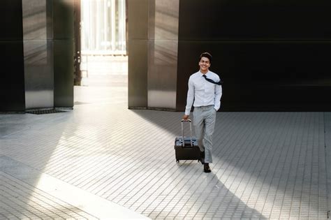 Premium Photo Happy Young Businessman Walking With Suitcase In The