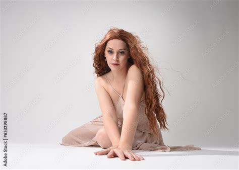 Full Length Portrait Of Beautiful Brunette Model Wearing A Pink Dress Graceful Sitting Pose
