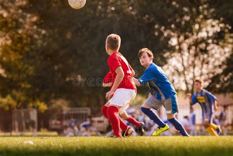 Meninos Que Jogam O Jogo De Futebol Do Futebol No Campo De Esportes