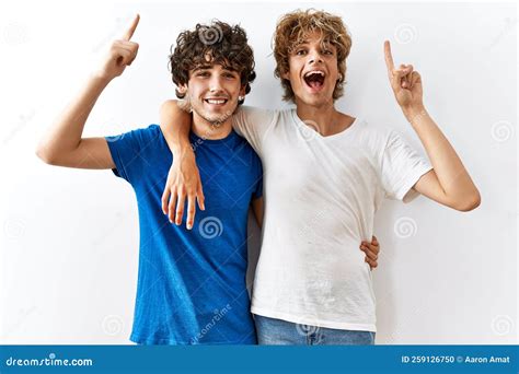 Joven Pareja Gay Parado Juntos En Un Contexto Aislado Sonriendo Asombrado Y Sorprendido Y