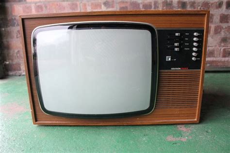 An Old Fashioned Television Sitting On Top Of A Green Floor Next To A