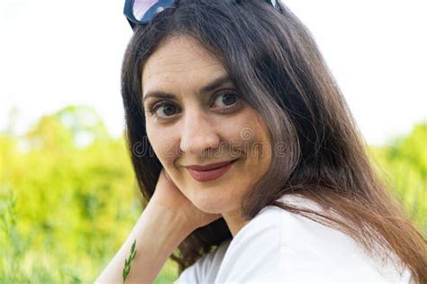 Portrait Of A 35 Year Old Brunette Woman Looking At The Camera Smiling In Nature Stock Photo
