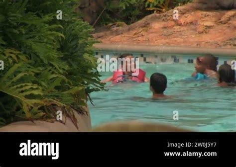A Close Up From Behind Of People Wearing Life Jackets Floating By In A Fast Flowing Lazy River