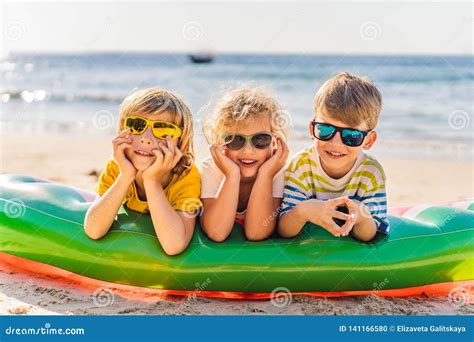 Drie Blonde Jonge Geitjes In Zonnebril Liggen Op Het Strand Stock Foto Image Of Blij Emmer