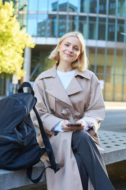 Une Photo Verticale D Une Jeune Femme Blonde Assise Sur Un Banc De Rue Avec Un T L Phone