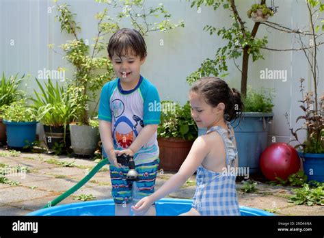 Siblings Playing With Water In The Backyard On A Hot Summer Day Stock Photo Alamy
