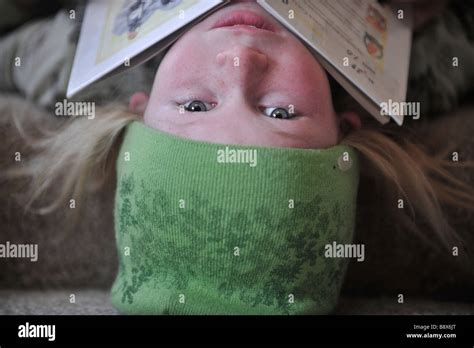 Little Girl Upside Down With A Book Resting On Her Chin Stock Photo Alamy