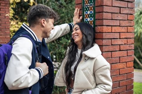 Premium Photo College Boy With Backpack Seducing Latina Girl Leaning On Wall