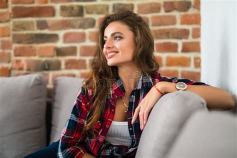 Smiling Beautiful Brunette Relaxing On The Couch And Looking At Camera