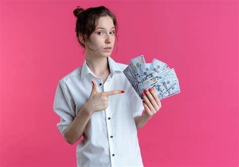 Jeune fille russe blonde confiante détient et points à l argent sur rose avec copie espace