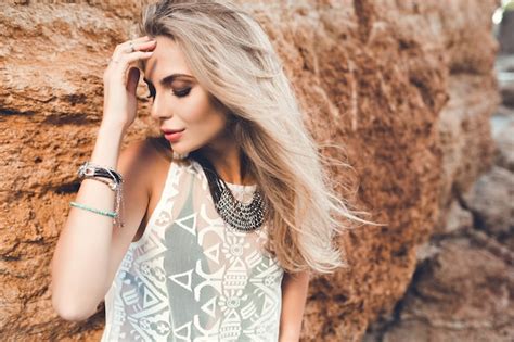 Portrait de gros plan de fille blonde aux cheveux longs posant à la caméra sur fond de pierre