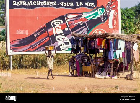 Burkina Faso. A market stall with clothes in front of a Coca Cola