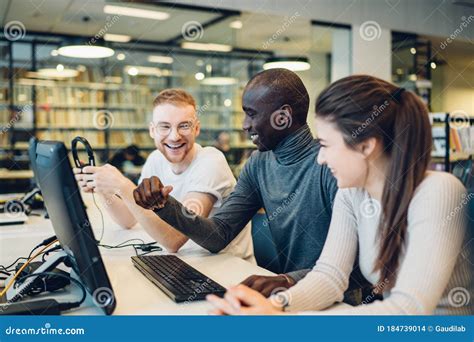 Étudiants Multiraciaux Gay S amusant Tandis Qu à L aide De L ordinateur Dans La Bibliothèque