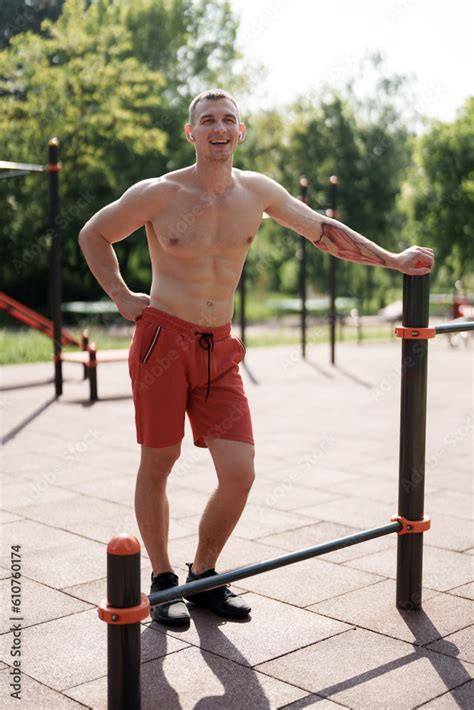 Full Body Of Smiling Muscular Male Athlete With Naked Torso Standing On