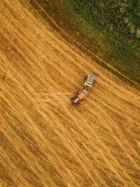 Aerial View Of Tractor Making Hay Bale Rolls In Field Stock Photo