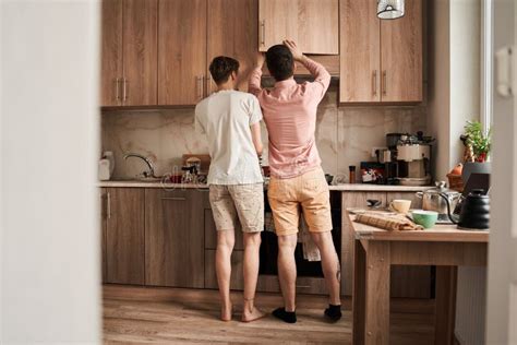 Gay Couple Looking For Something At The Shelfs At The Kitchen Stock Photo Image Of Domestic