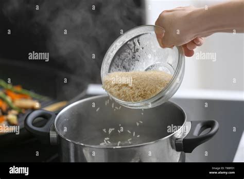 Woman Pouring Rice Into Saucepan With Boiling Water Stock Photo Alamy