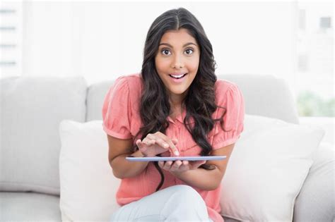 Premium Photo Excited Cute Brunette Sitting On Couch Holding Tablet