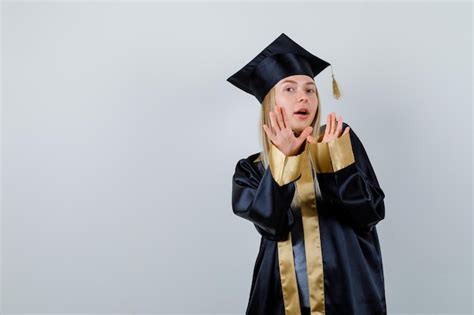 Fille blonde s étendant les mains pour s arrêter en robe de graduation et casquette et avoir
