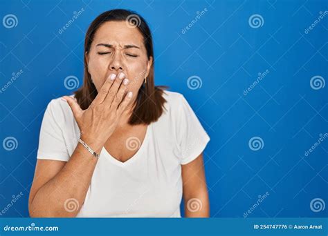 Hispanic Mature Woman Standing Over Blue Background Bored Yawning Tired