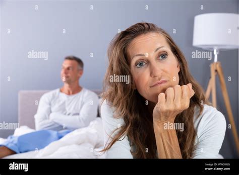 Unhappy Mature Couple Sitting On Bed In Bedroom Stock Photo Alamy