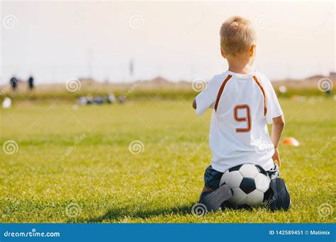 Bambino Che Si Siede Sul Pallone Da Calcio Sul Campo Da Calcio Bambino