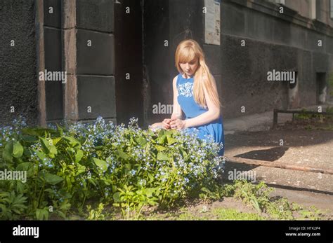 Woman Blonde In A Blue Dress Walking Along A City Street Against A Background Of Urban