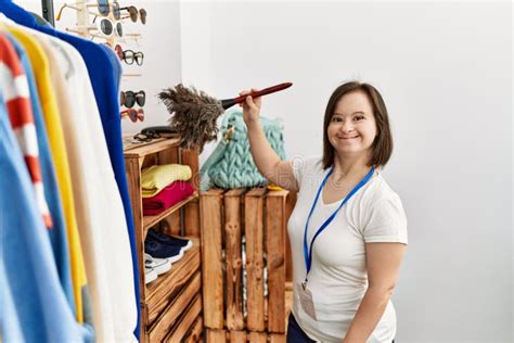 Brunette Woman With Down Syndrome Working As Shop Assistant Cleaning Dust At Retail Shop Stock