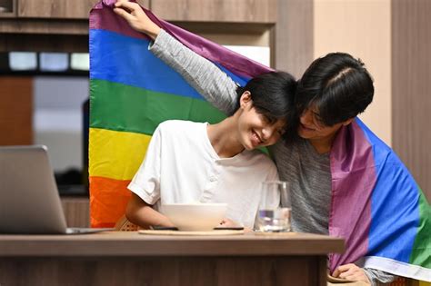 Jovem casal gay abraçando e mostrando seu amor a bandeira do arco íris conceito de liberdade