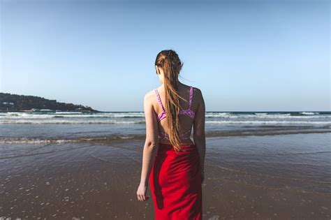 Junge Frau Tr Gt Ein Rotes Handtuch Und Einen Rosa Bikini Zu Fu Am Wasserrand Am Strand