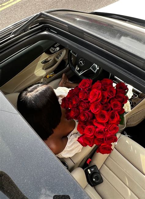 A Man Sitting In The Back Seat Of A Car Holding A Bouquet Of Red Roses