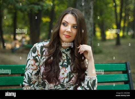 Beautiful Brunette Girl Poses On Bench In Park Outdoors Stock Photo Alamy