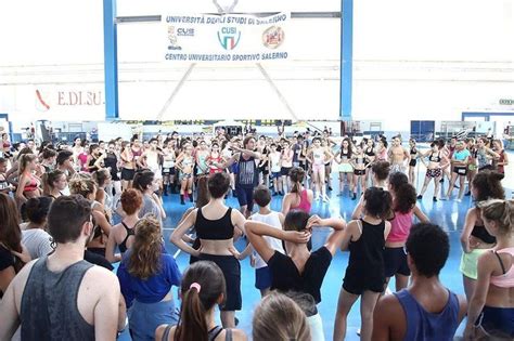 A Large Group Of People Standing Around Each Other In A Gym With One