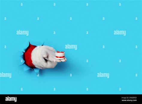 Santa Holding Small T Box In His Hand Isolated Over Lignt Blue Stock