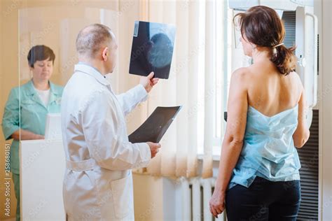 Male Octor Standing Assisting Female Patient Undergoing Mammogram X Ray