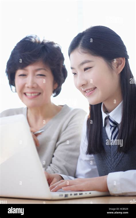 Portrait Of Smiling Middle School Girl And Smiling Mother Using