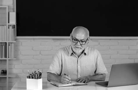 Aged Male Retired Teacher Portrait Of Mature Teacher Or Tutor Professor Working At Table In
